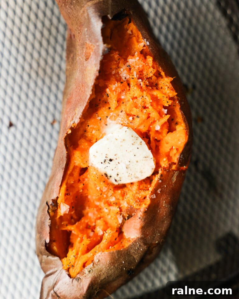 Delicious Sweet Potato Recipes for Every Meal 13 An overhead shot of an air fryer sweet potato, cut open and topped with butter, salt, and pepper.