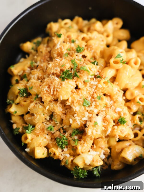 Delicious Sweet Potato Recipes for Every Meal 32 A close-up shot of vegan butternut squash mac and cheese in a black bowl with panko breadcrumbs.