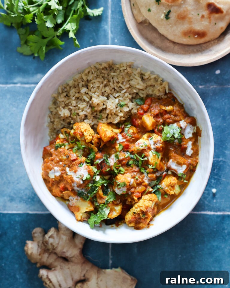 Delicious Sweet Potato Recipes for Every Meal 7 overhead of vegan tempeh tikka masala in a white bowl on a blue tile counter.