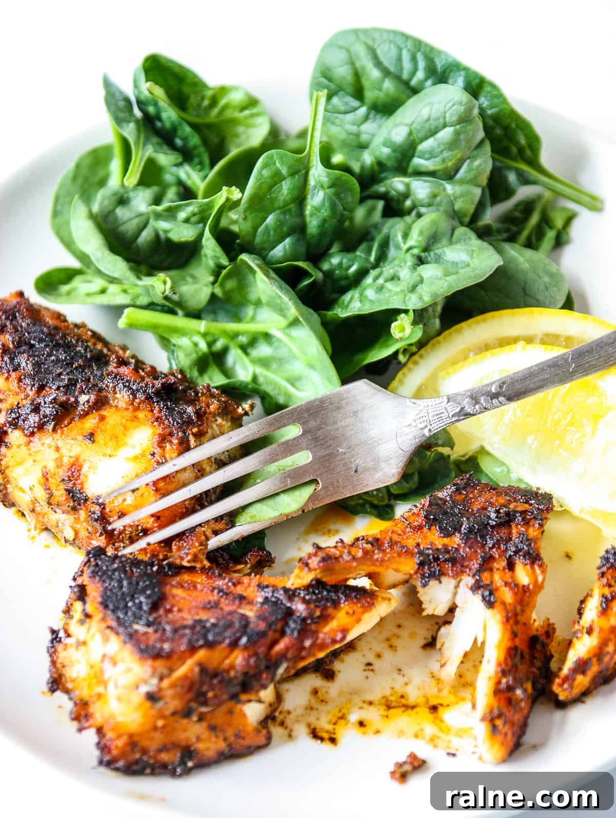 Cajun Blackened Cod Recipe — Crispy Spiced Pan-Seared Fish 3 A silver fork cutting into a pan seared fish fillet.