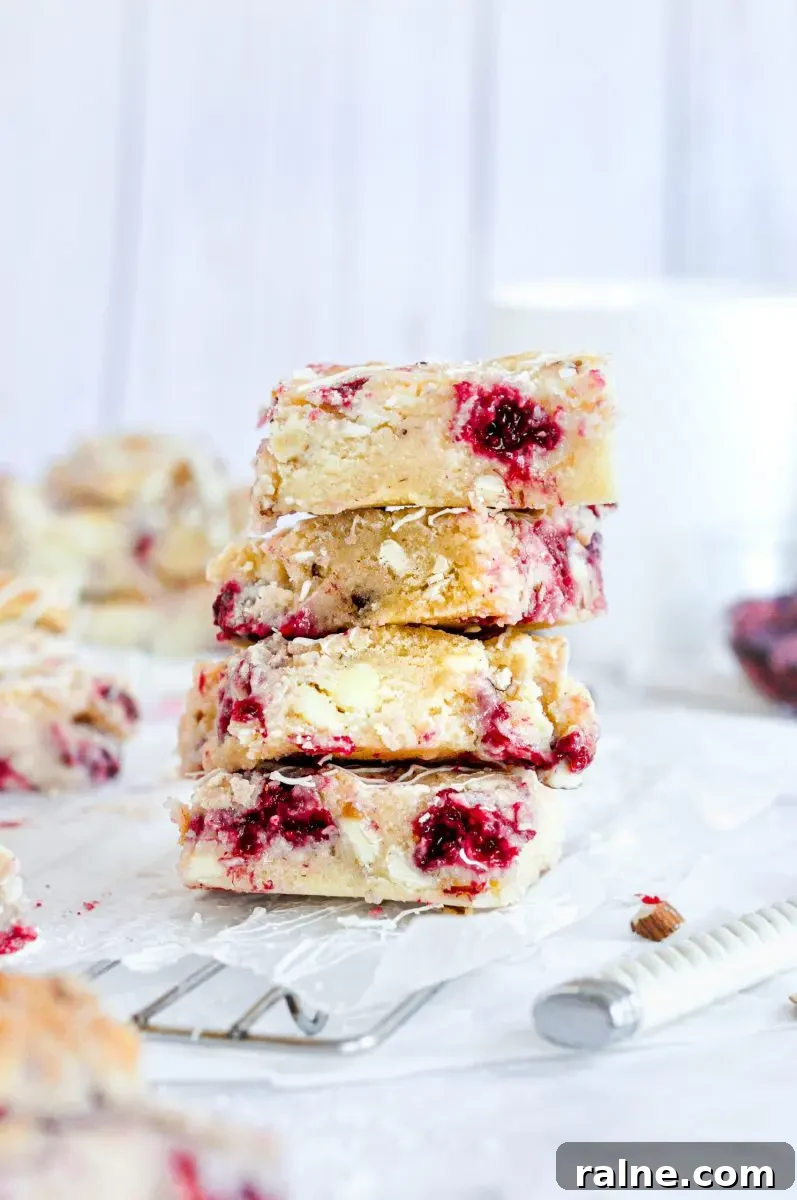 Raspberry Blondies with Oat Streusel — Chewy, Fruity Bars 4 A stack of 4 blondie squares full of raspberries and white chocolate chips.