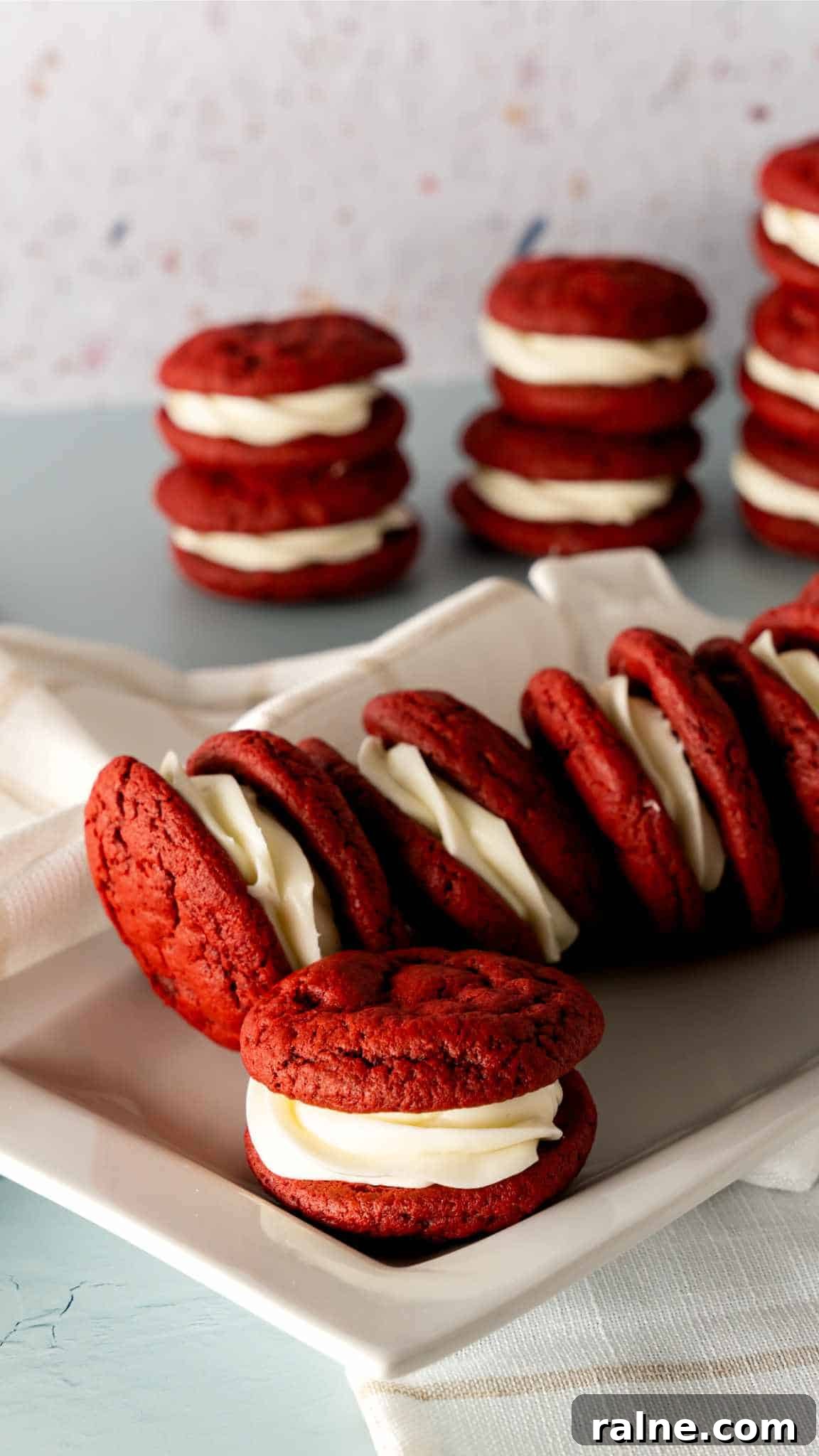 Decadent Red Velvet Whoopie Pies Recipe for Perfect Sandwich Cookies 3 Red Velvet Whoopie Pies spread out on a rectangular white plate.