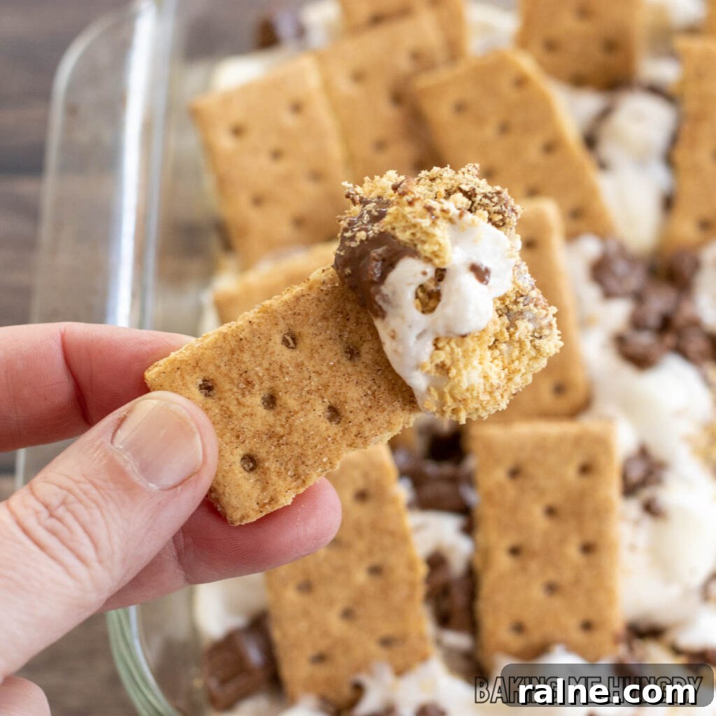 Decadent S'mores Casserole Recipe for Family Desserts 11 oven baked s'mores dip recipe shown scooped onto a graham cracker
