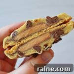 Peanut Butter Cup Stuffed Cookies: Gooey Chocolate Surprise 5 the author is holding a split open PB cup stuffed chocolate chip cookie to show the inside of the cookie