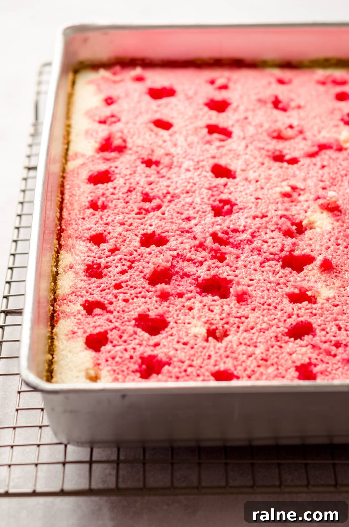 Strawberry Jello Poke Cake Recipe — Moist, Creamy Dessert 12 strawberry poke cake with jello poured over it