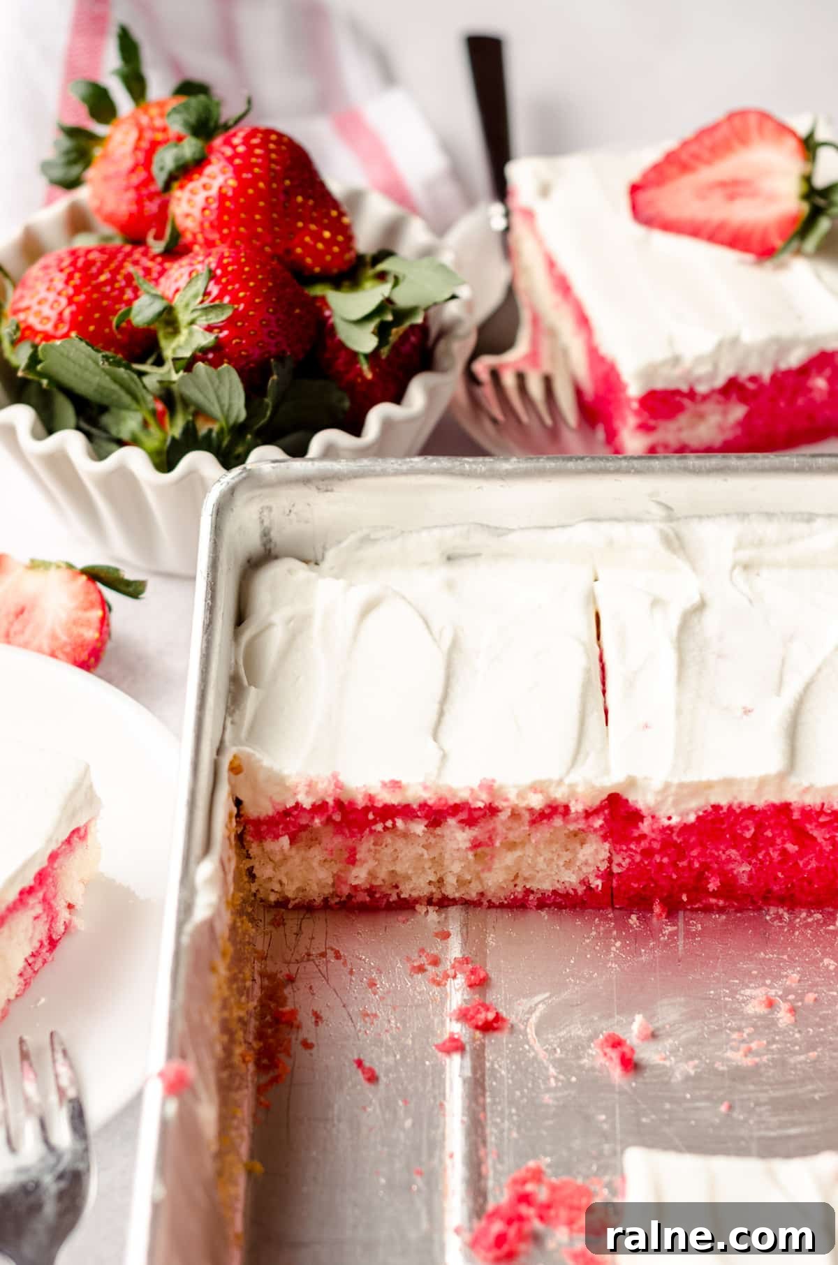 Strawberry Jello Poke Cake Recipe — Moist, Creamy Dessert 4 strawberry poke cake sliced in a sheet pan