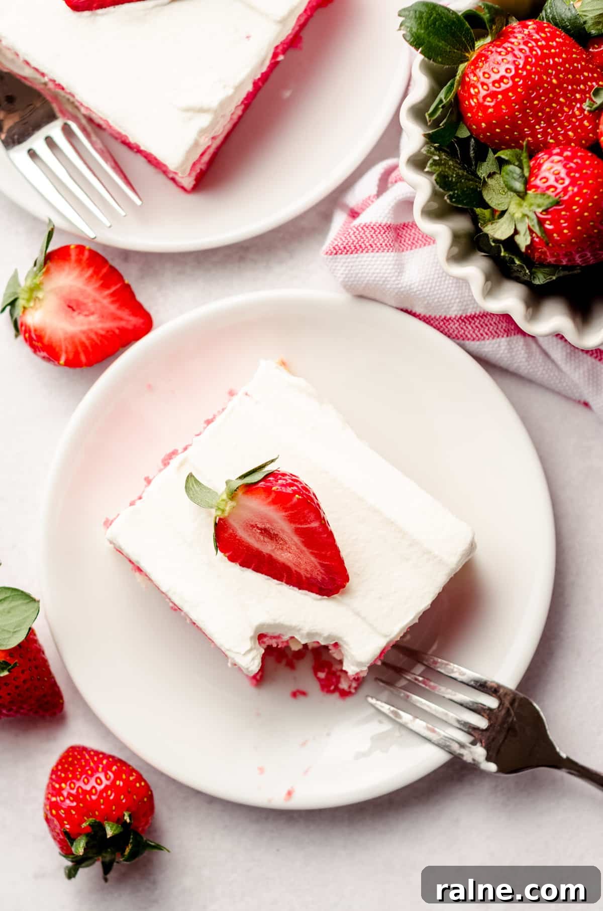 Strawberry Jello Poke Cake Recipe — Moist, Creamy Dessert 5 aerial photo of slice of strawberry poke cake on a plate with a bite taken out of it with a fork