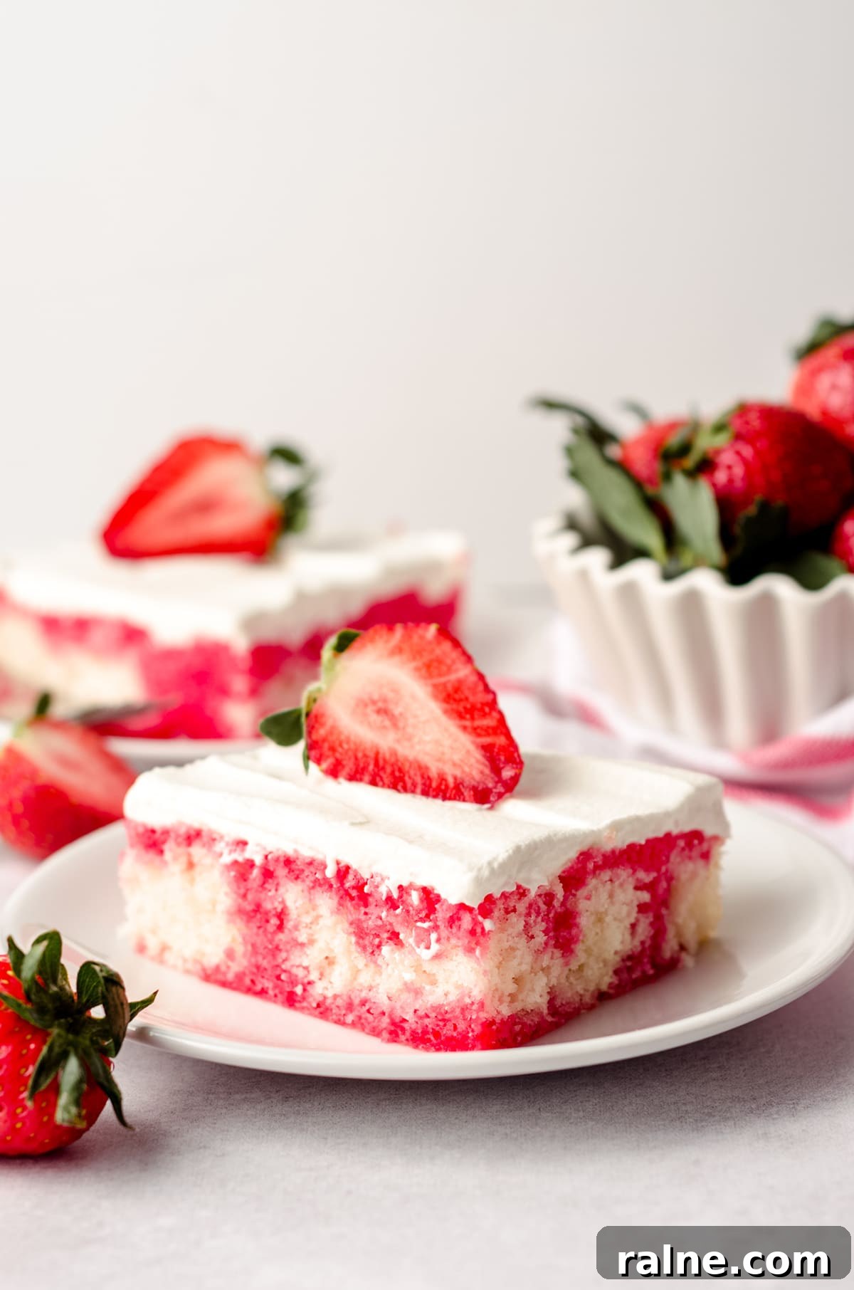 Strawberry Jello Poke Cake Recipe — Moist, Creamy Dessert 7 slice of strawberry poke cake on a plate