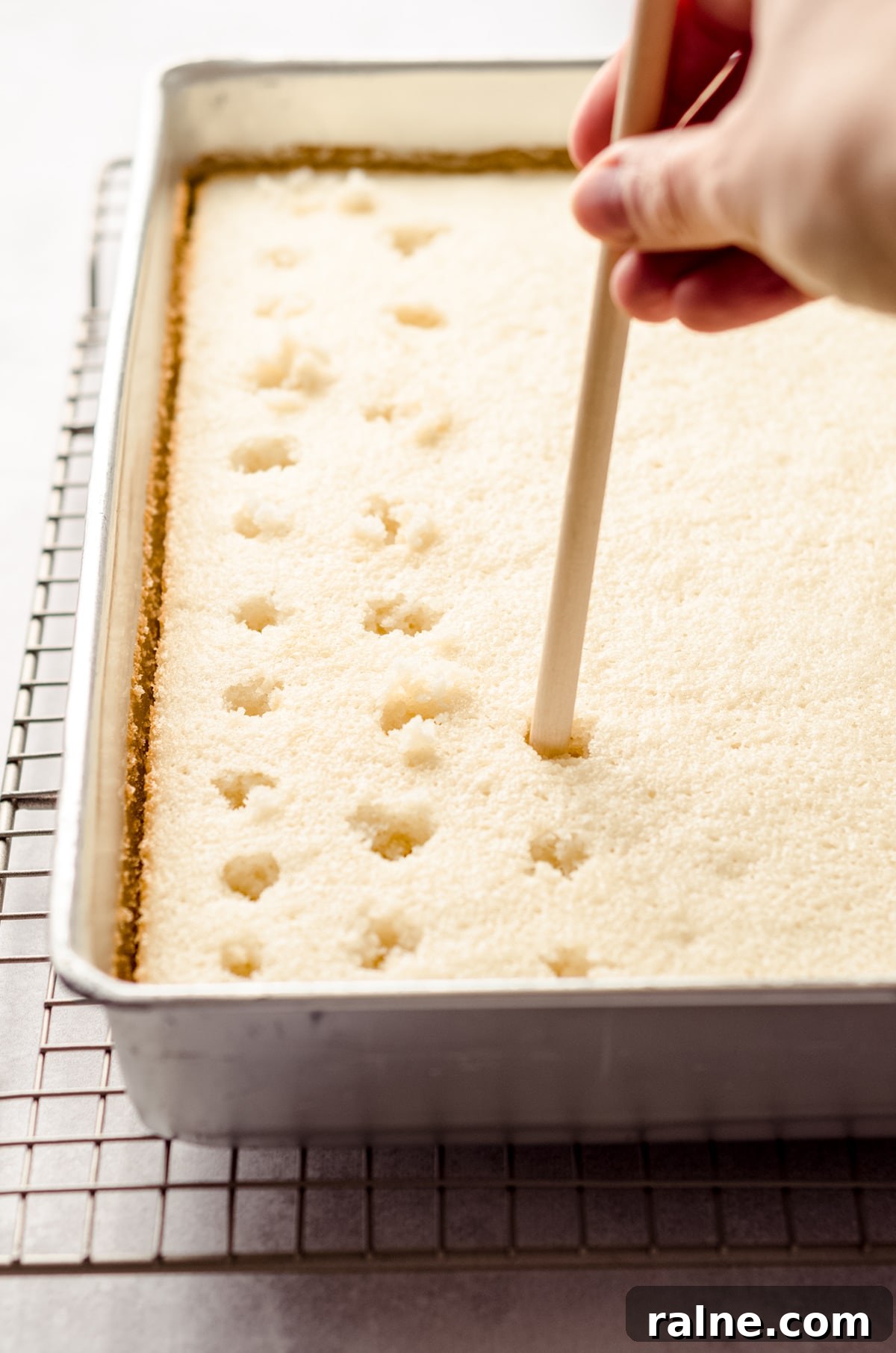 Strawberry Jello Poke Cake Recipe — Moist, Creamy Dessert 9 poking holes in a sheet cake to make strawberry poke cake