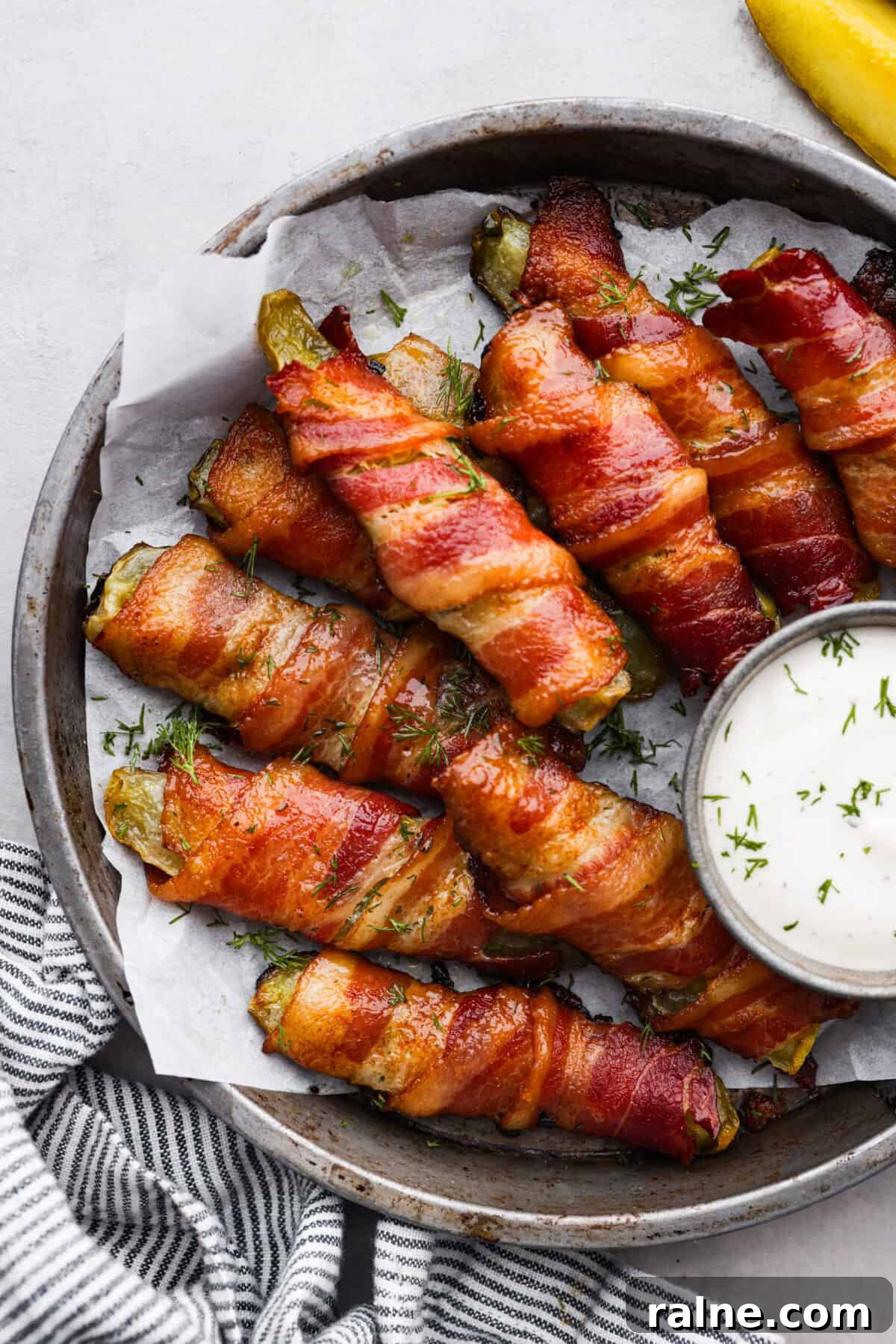 Bacon Wrapped Pickles Bacon wrapped pickles in a gray serving bowl, served with a side of ranch dressing.