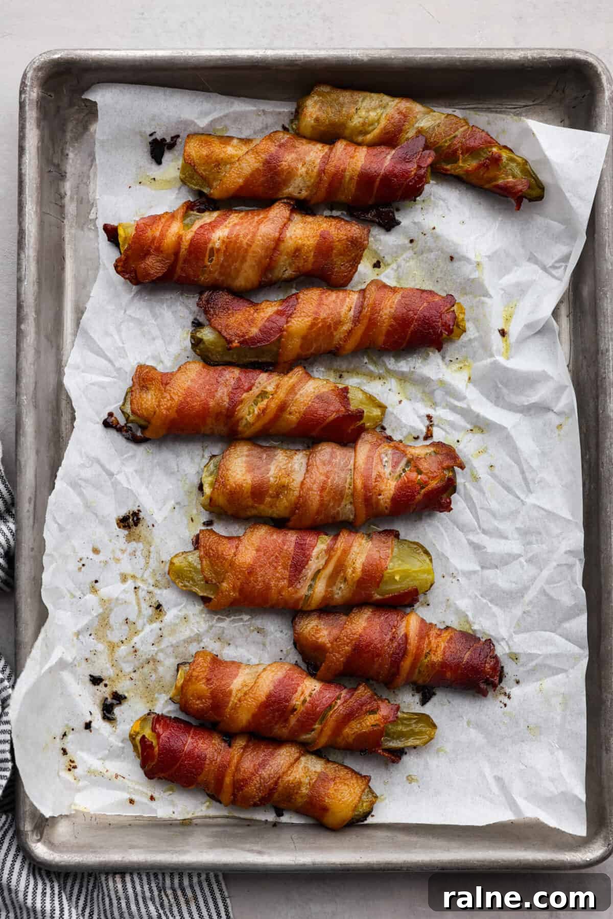 Bacon wrapped pickles on a baking sheet Bacon wrapped pickles on a baking sheet.