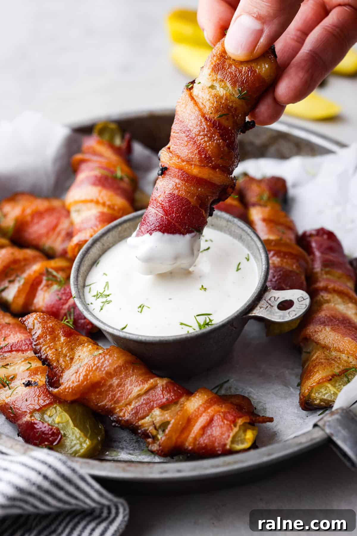 Dipping a bacon wrapped pickle into ranch Dipping a pickle into ranch.