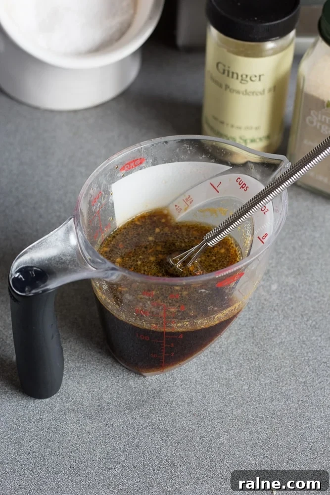 Stir fry sauce in a measuring cup with a whisk on a gray countertop.