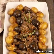 Slow Cooker Beef Pot Roast with Mushrooms and Red Wine香 5 A serving platter of sliced slow-cooker pot roast surrounded by braised mushroom caps and baby potatoes, garnished with a sprig of fresh thyme.