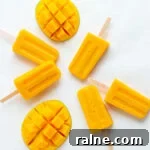 Overhead photo of mango popsicles and fresh mango halves on a white background.