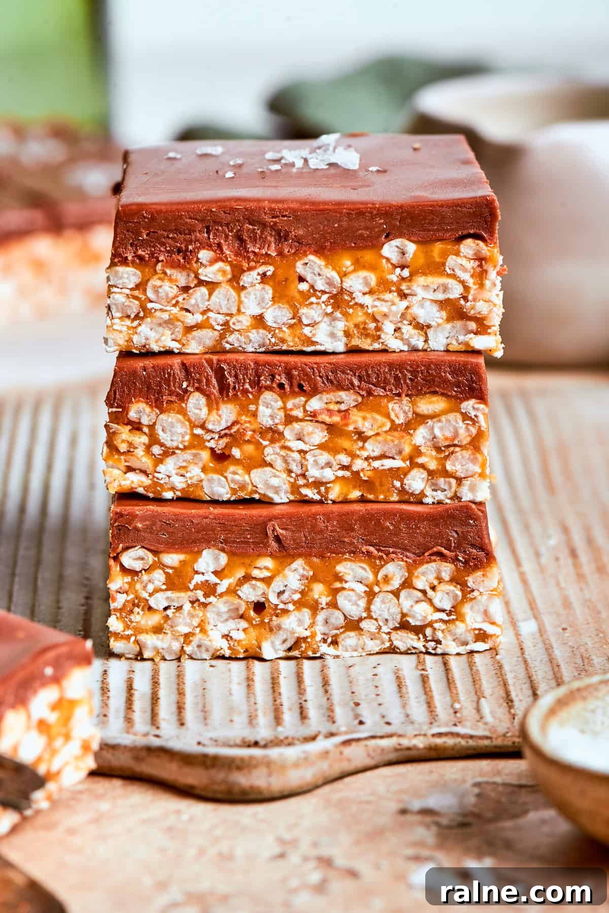 No-bake scotcharoos feature creamy peanut butter, crispy rice cereal, and a sweet layer of melted chocolate and butterscotch. Three scotcharoos stacked on top of each other.