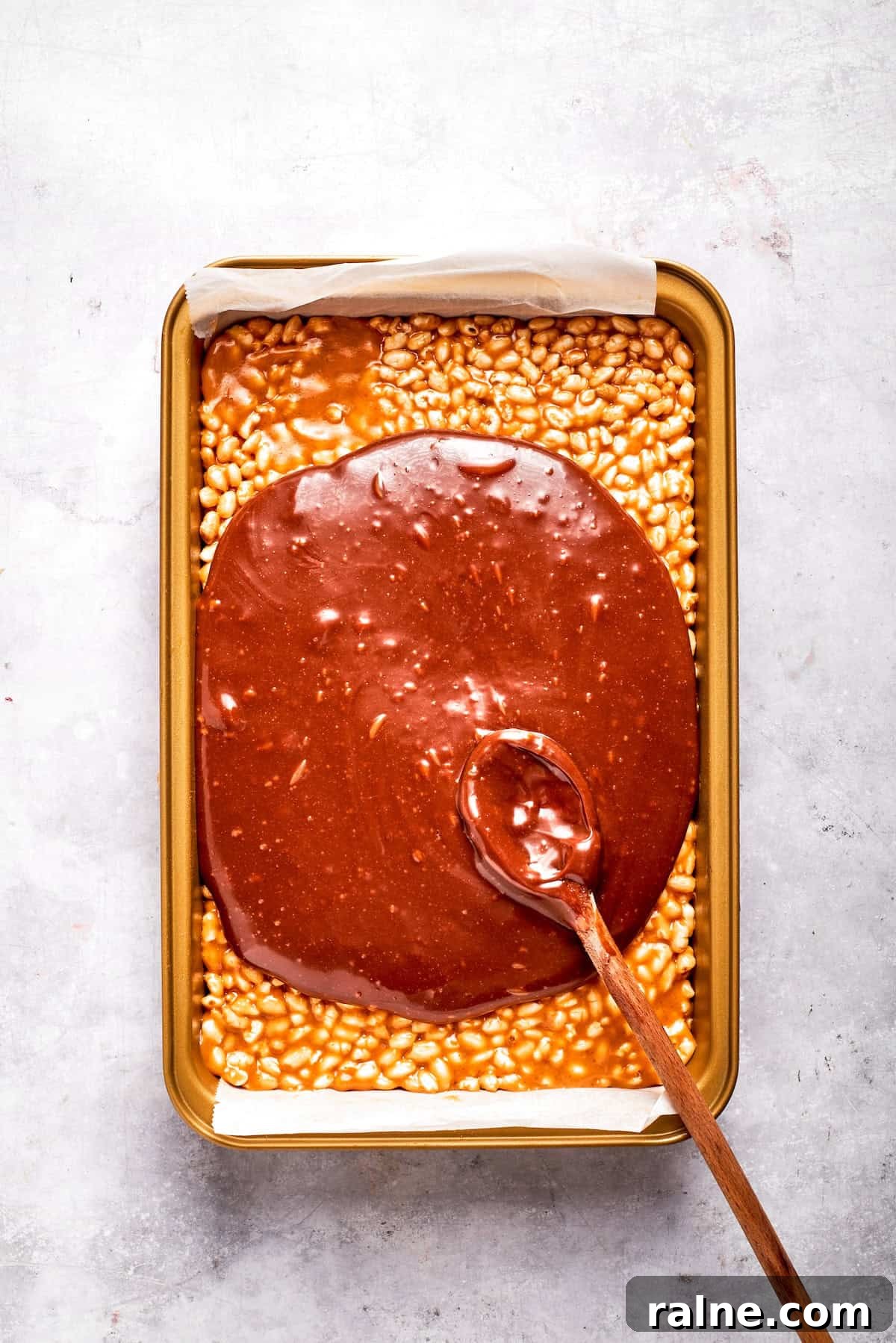 No-bake scotcharoos feature creamy peanut butter, crispy rice cereal, and a sweet layer of melted chocolate and butterscotch. Melted chocolate and butterscotch is spread over a pan of scotcharoos.