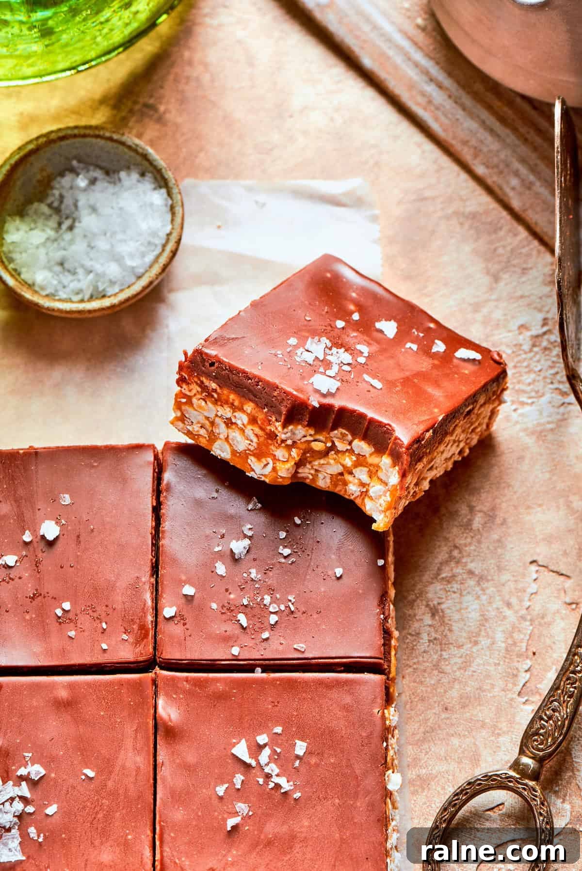 No-bake scotcharoos feature creamy peanut butter, crispy rice cereal, and a sweet layer of melted chocolate and butterscotch. A scotcharoo with a bite taken out.