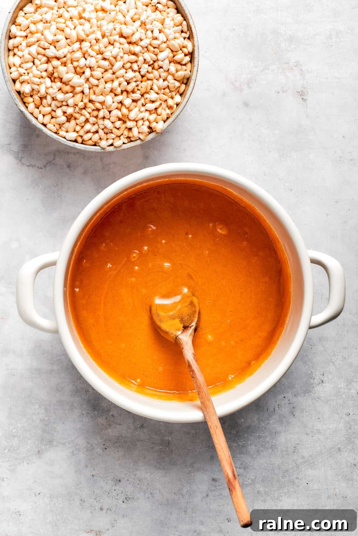 No-bake scotcharoos feature creamy peanut butter, crispy rice cereal, and a sweet layer of melted chocolate and butterscotch. Melted butter and peanut butter in a pot.
