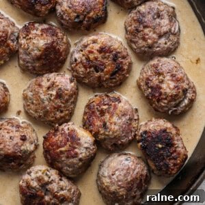 A skillet containing several browned meatballs in a creamy gravy.