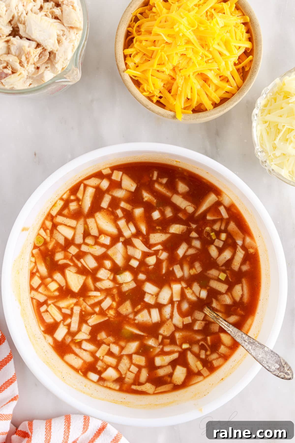 turkey enchilada sauce mixture combined in a mixing bowl with spoon