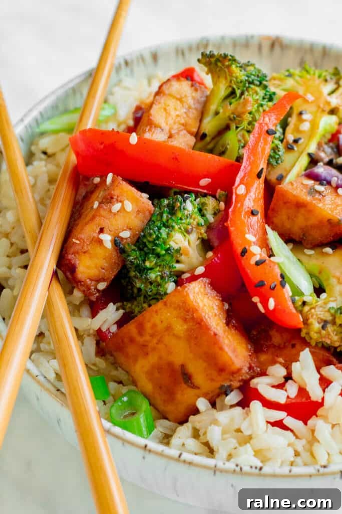Close up of Crispy Tofu Hoisin Stir-fry in bowl with chopsticks. Vegan, GF & Healthy! Georgie Eats.