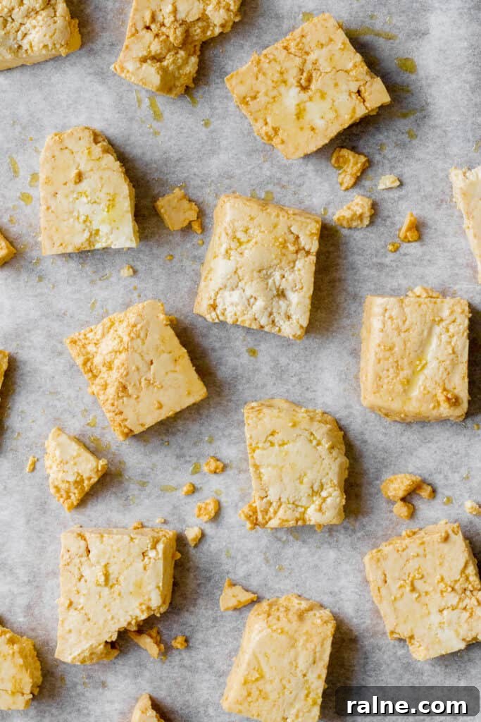 Chunks of uncooked tofu on baking tray.