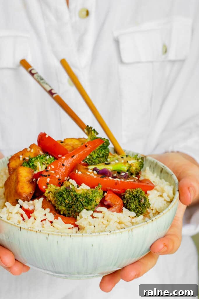 Woman holding bowl of Crispy Tofu Hoisin Stir-fry. Vegan, GF & Healthy! Georgie Eats.