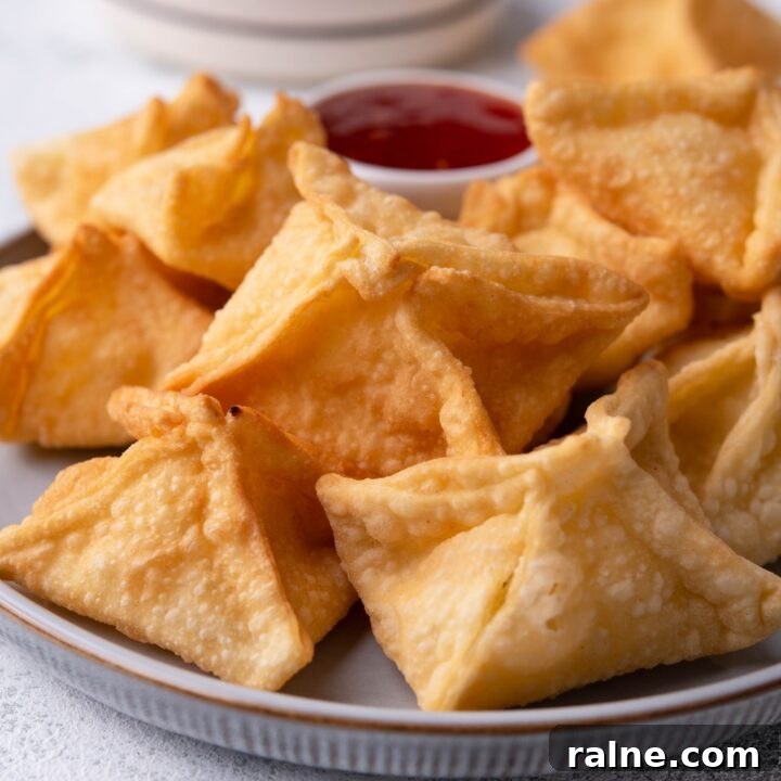 Close up of Panda Express cream cheese rangoon piled on a grey plate with a dipping sauce on the plate.