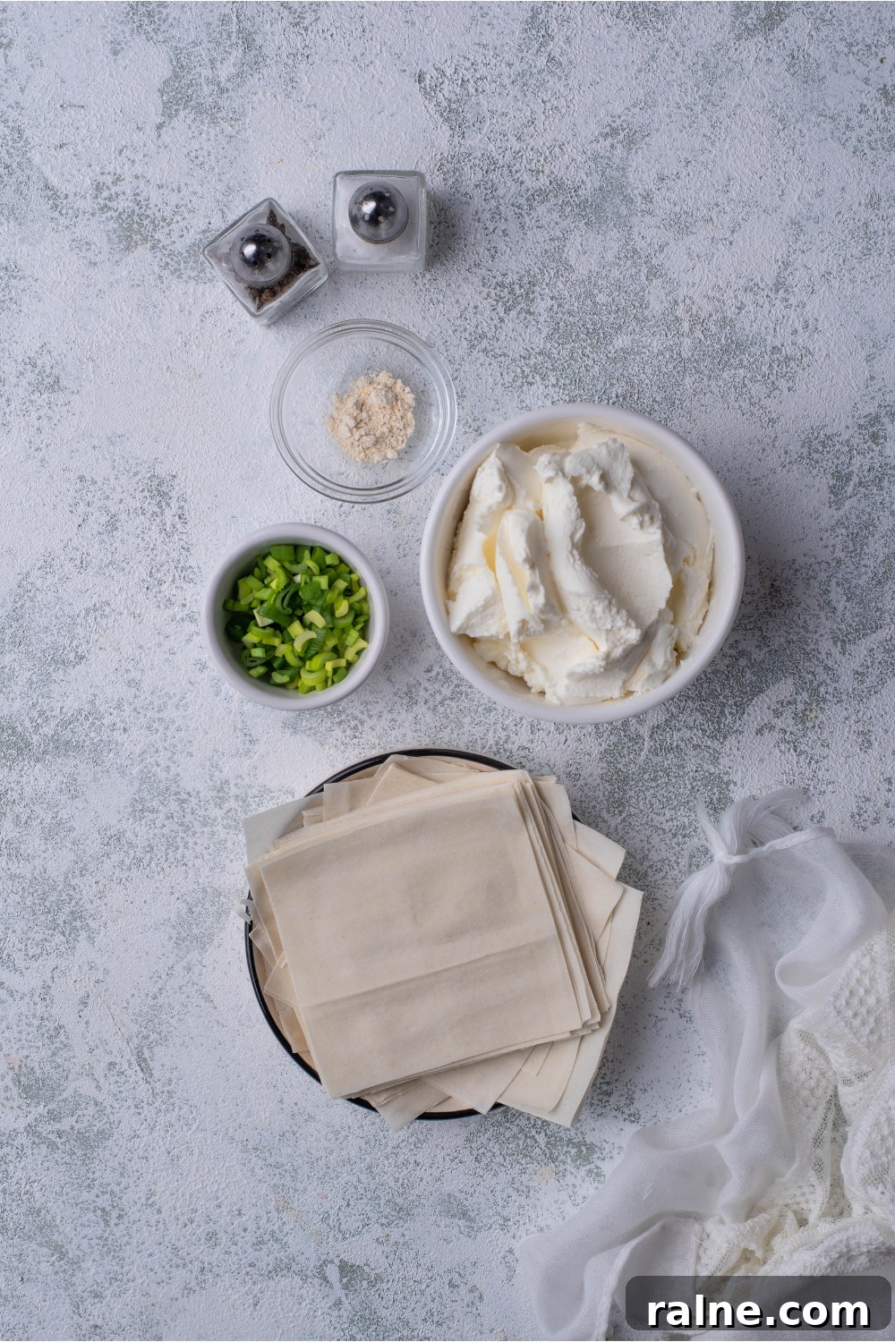 Crispy Cream Cheese Rangoon Wontons: Easy Homemade Recipe 4 An assortment of ingredients including bowls of cream cheese, diced green onion, wonton wrappers, and spices.