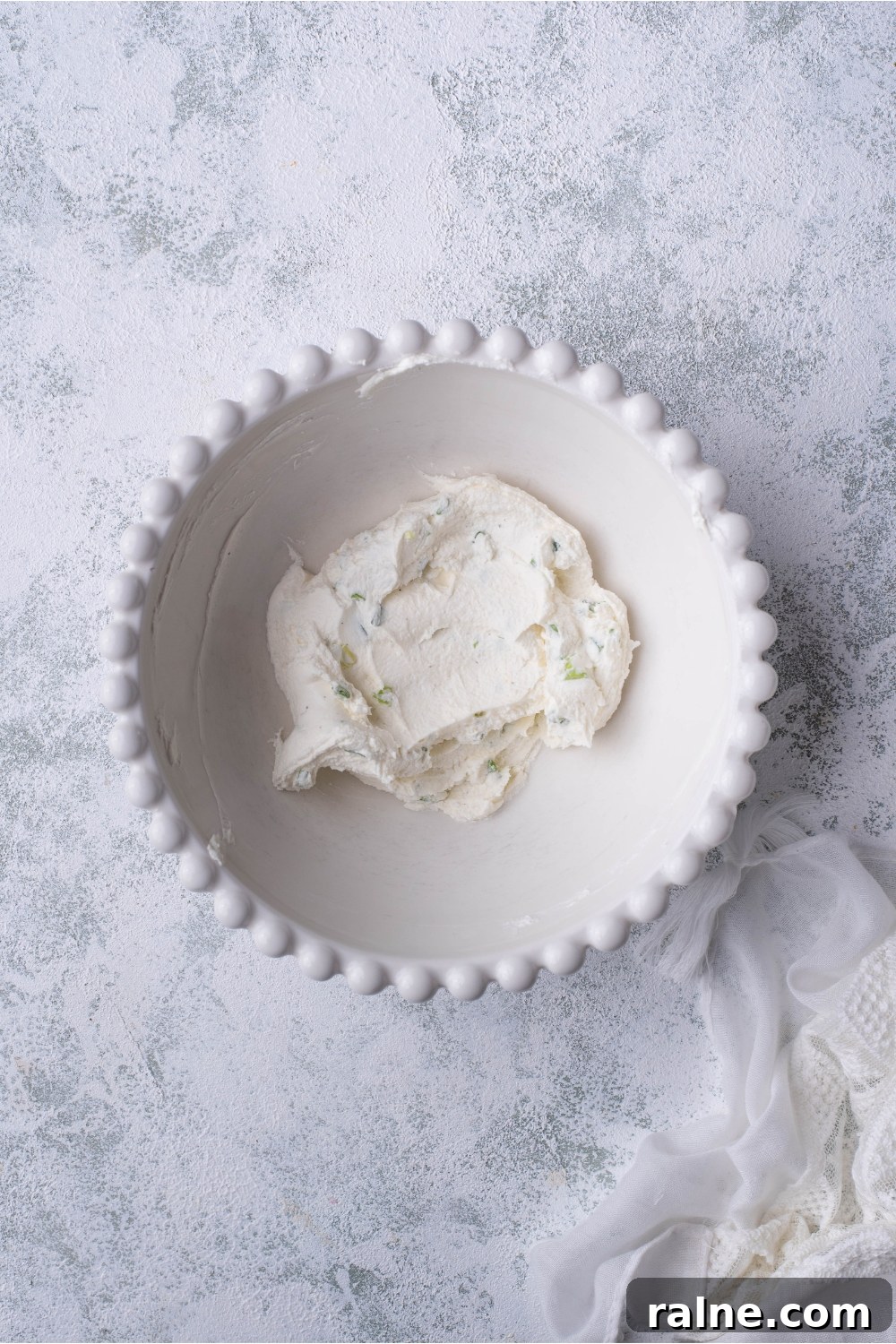 Crispy Cream Cheese Rangoon Wontons: Easy Homemade Recipe 6 A decorative white bowl filled with cream cheese and green onion that have been mixed together.