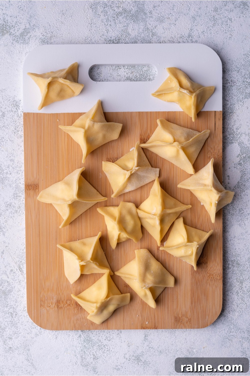 Crispy Cream Cheese Rangoon Wontons: Easy Homemade Recipe 8 Unbaked Panda Express cream cheese rangoon on a wood cutting board.