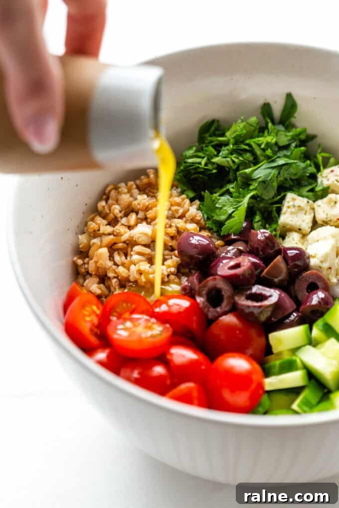 Mediterranean Farro Salad with Feta, Cucumber & Olives 5 Greek salad dressing being poured into a bowl of a farro salad