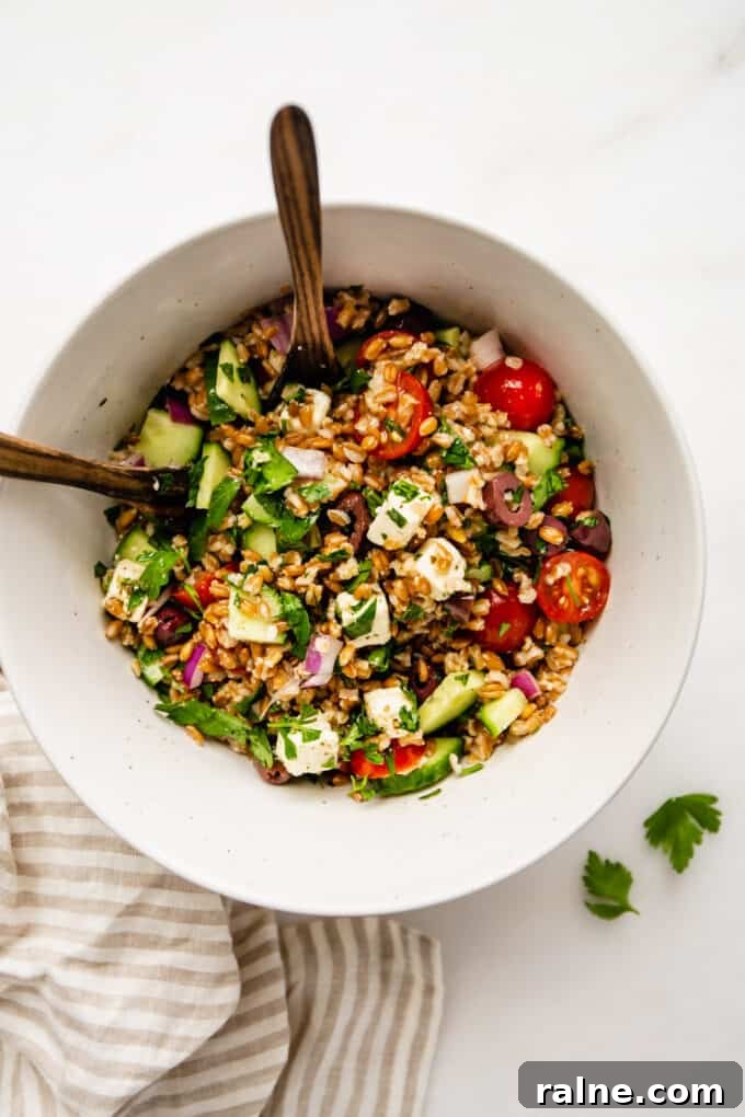 Mediterranean Farro Salad with Feta, Cucumber & Olives 6 Greek farro salad in a bowl with serving spoons and a striped napkin on the side