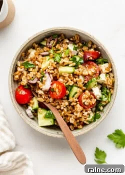 a bowl of Greek farro salad with a wood spoon in it