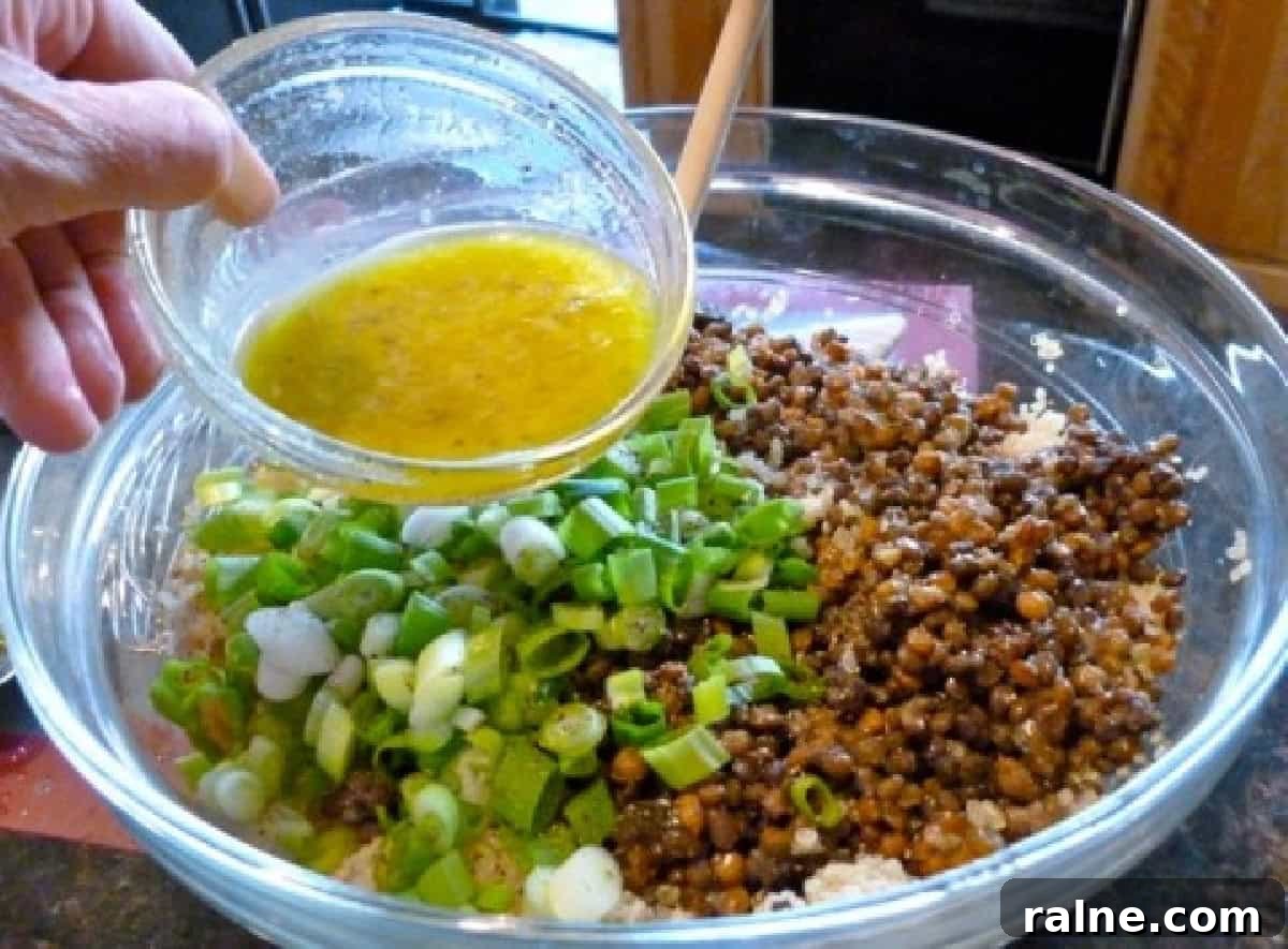Zesty Lemon Lentil and Quinoa Salad with Fresh Herbs 4 Adding Lemon Dressing to Large Glass Mixing Bowl of Quinoa, Lentils and Scallions