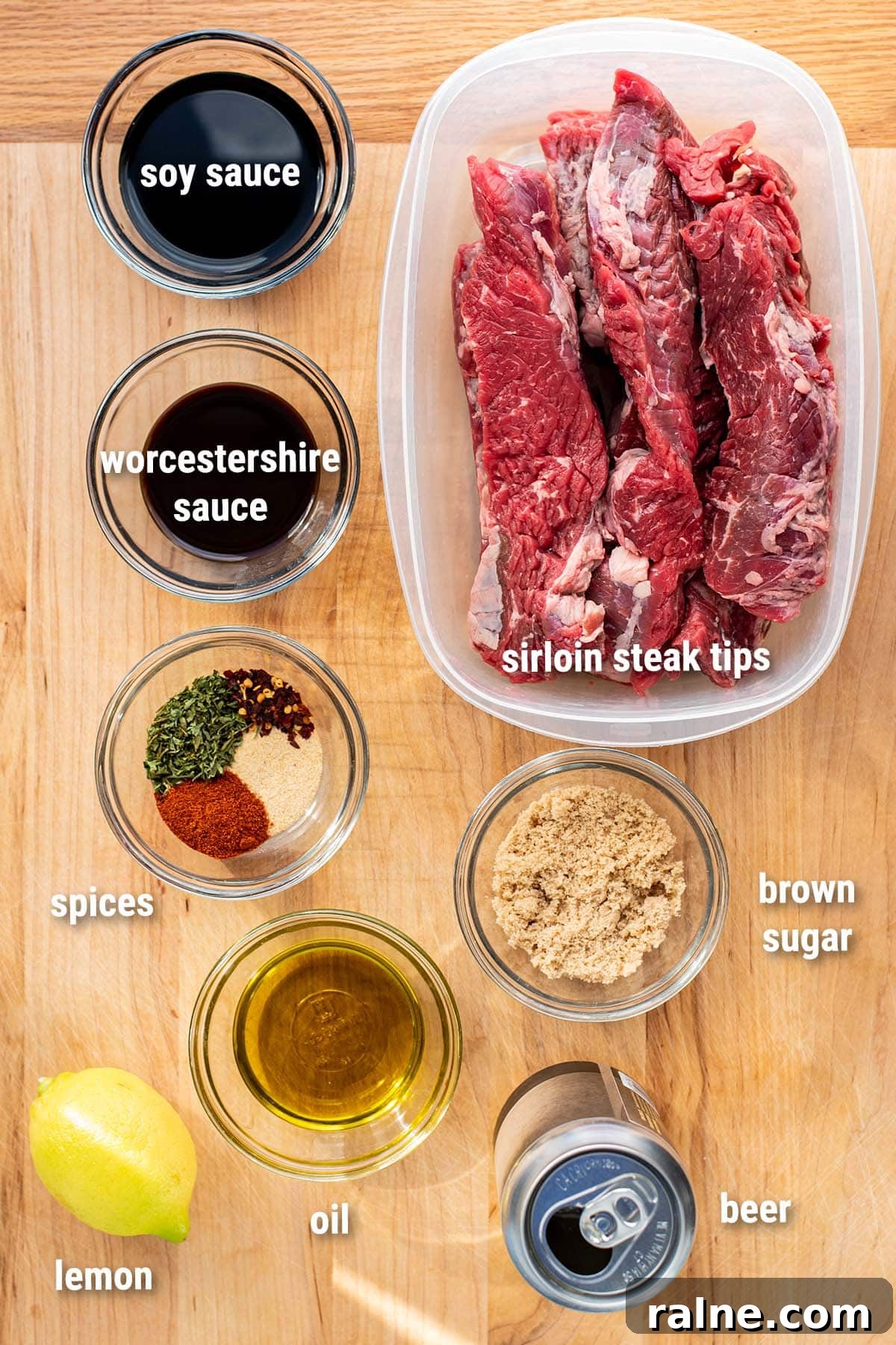 Beer Teriyaki Marinated Steak Tips Recipe 3 Raw, uncooked steak tips and homemade teriyaki marinade ingredients laid out on a wooden cutting board.