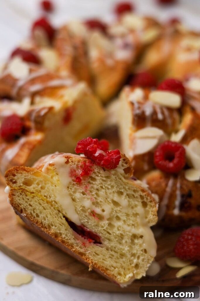Festive Braided Sourdough Brioche Wreath with Raspberries & Orange Glaze 3 A close up photo of the sourdough brioche braided wreath with a slice cut out and showing the crumb.