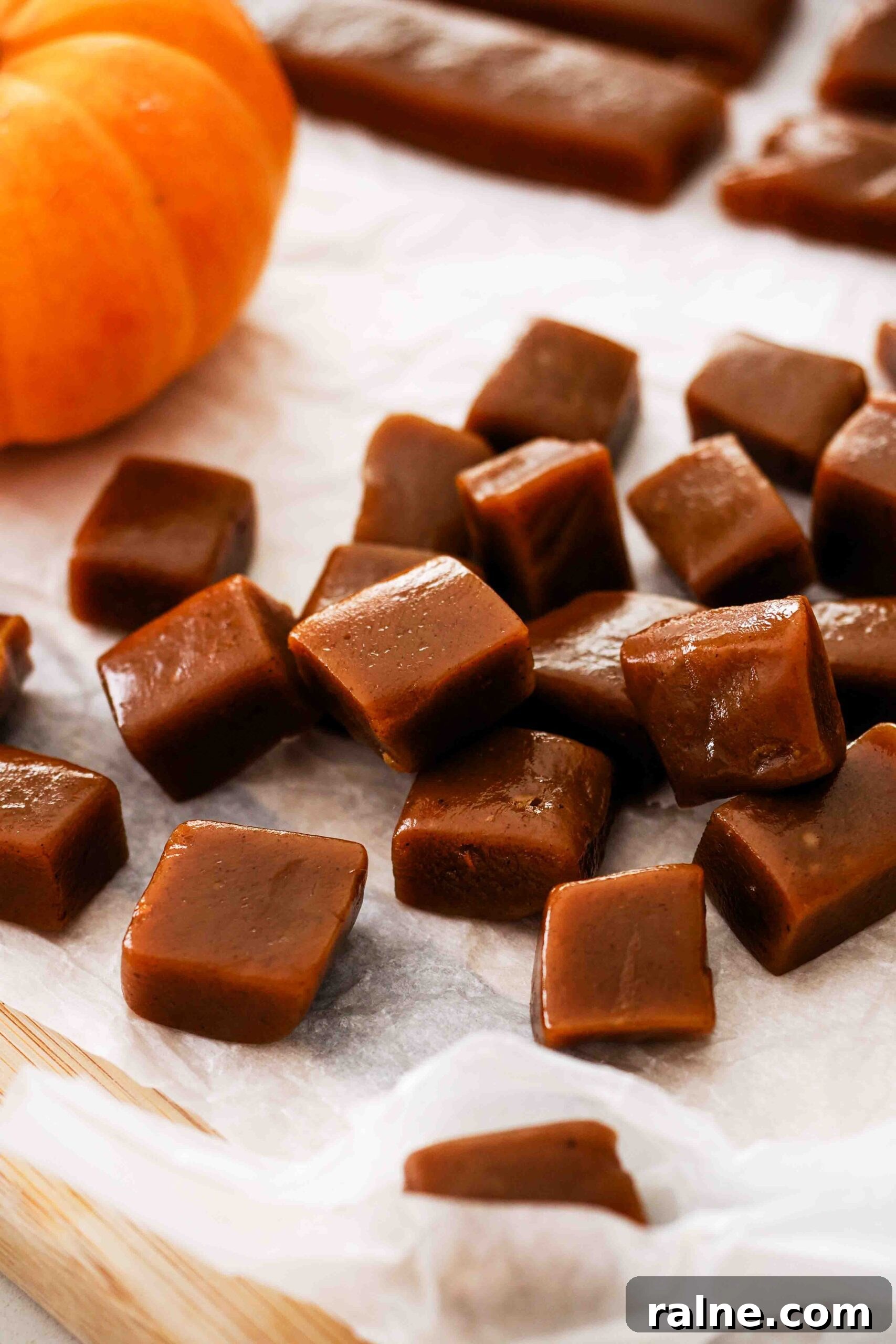 Pumpkin Spice Caramels Recipe: Homemade Fall Candy Guide 2 Freshly cut pumpkin spice caramels in a pile on a cutting board.