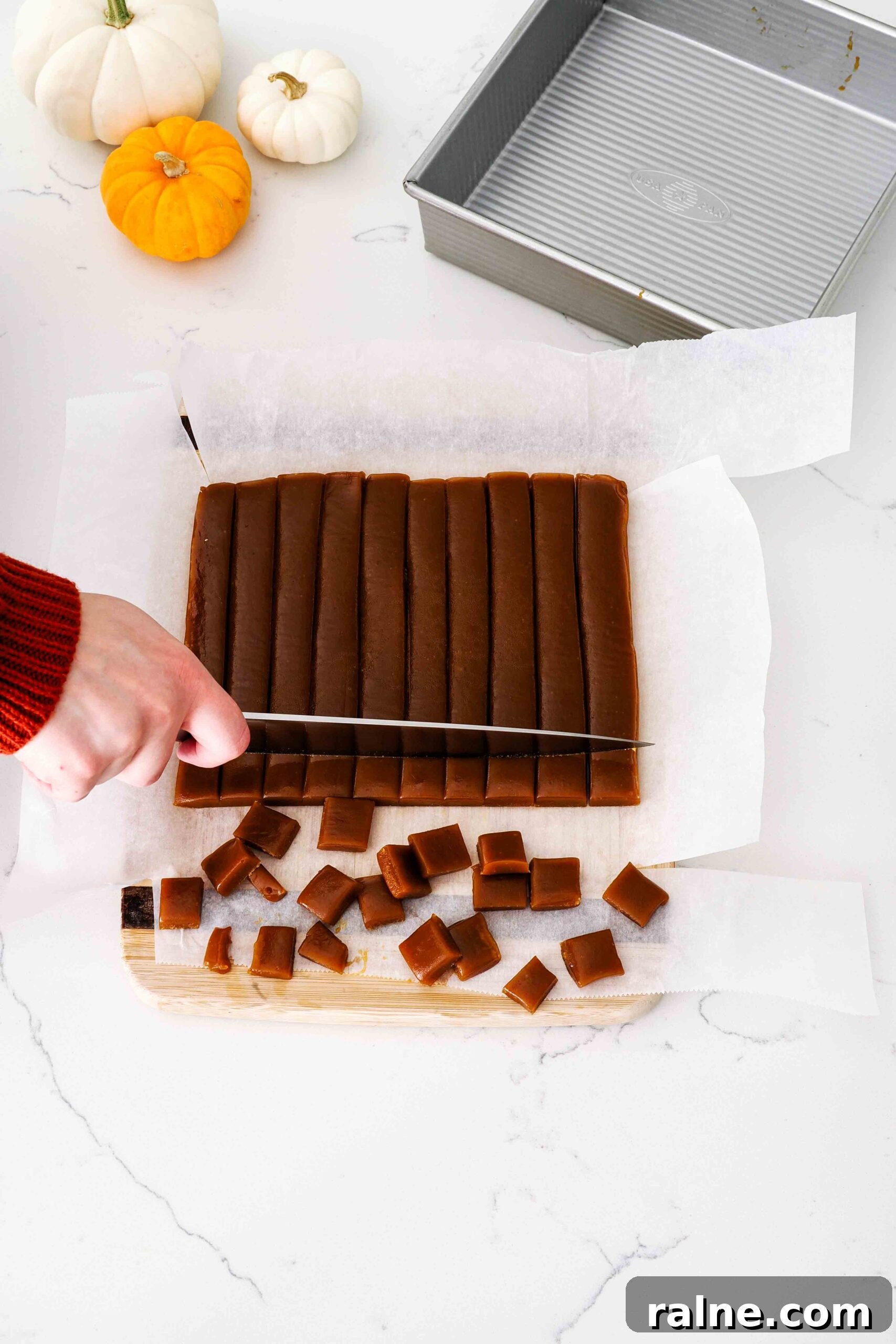 Pumpkin Spice Caramels Recipe: Homemade Fall Candy Guide 13 A knife cuts individual caramel candies out of a slab of pumpkin spice caramel.