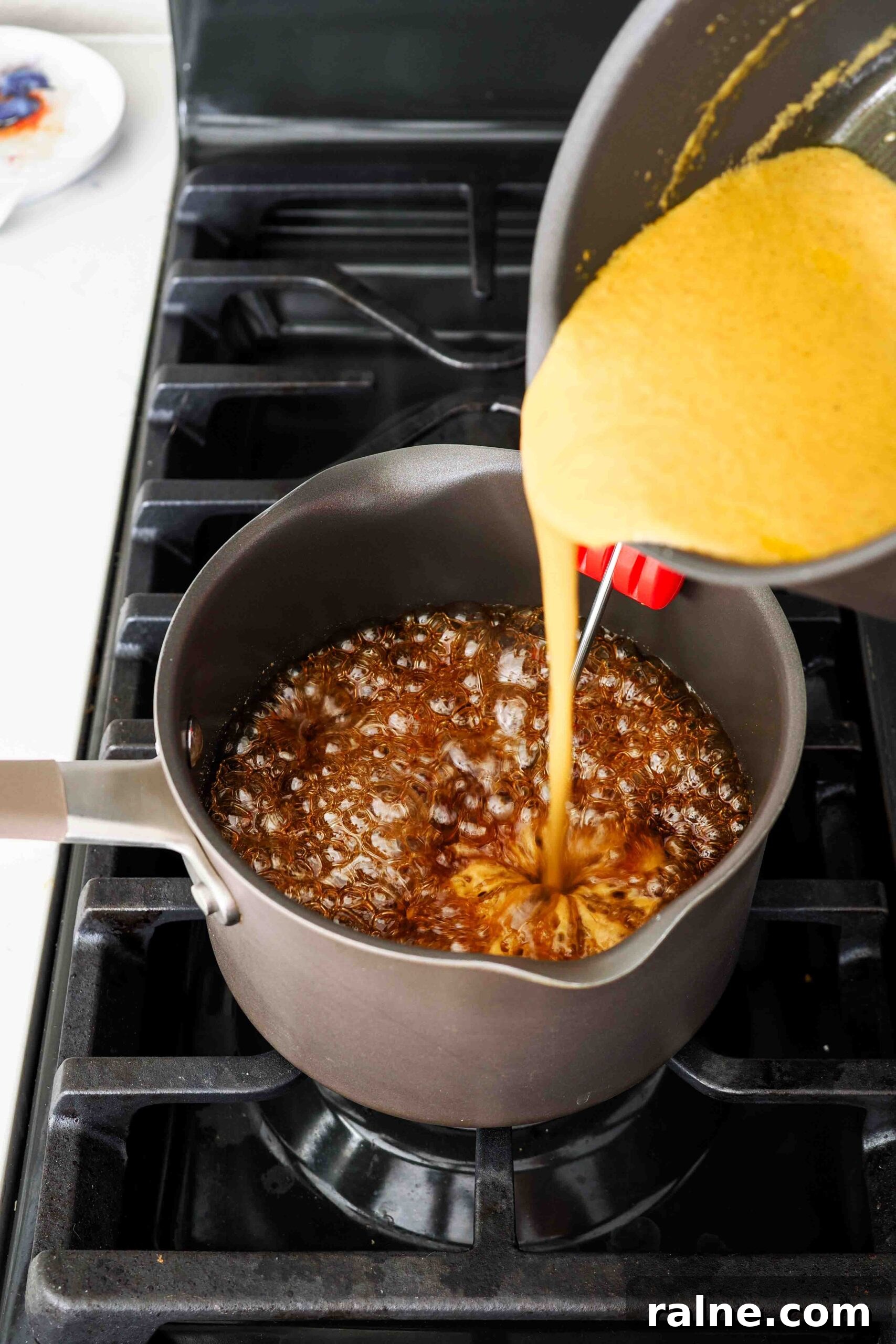 Pumpkin Spice Caramels Recipe: Homemade Fall Candy Guide 9 Pumpkin cream is poured into a pot of caramel over the stove.