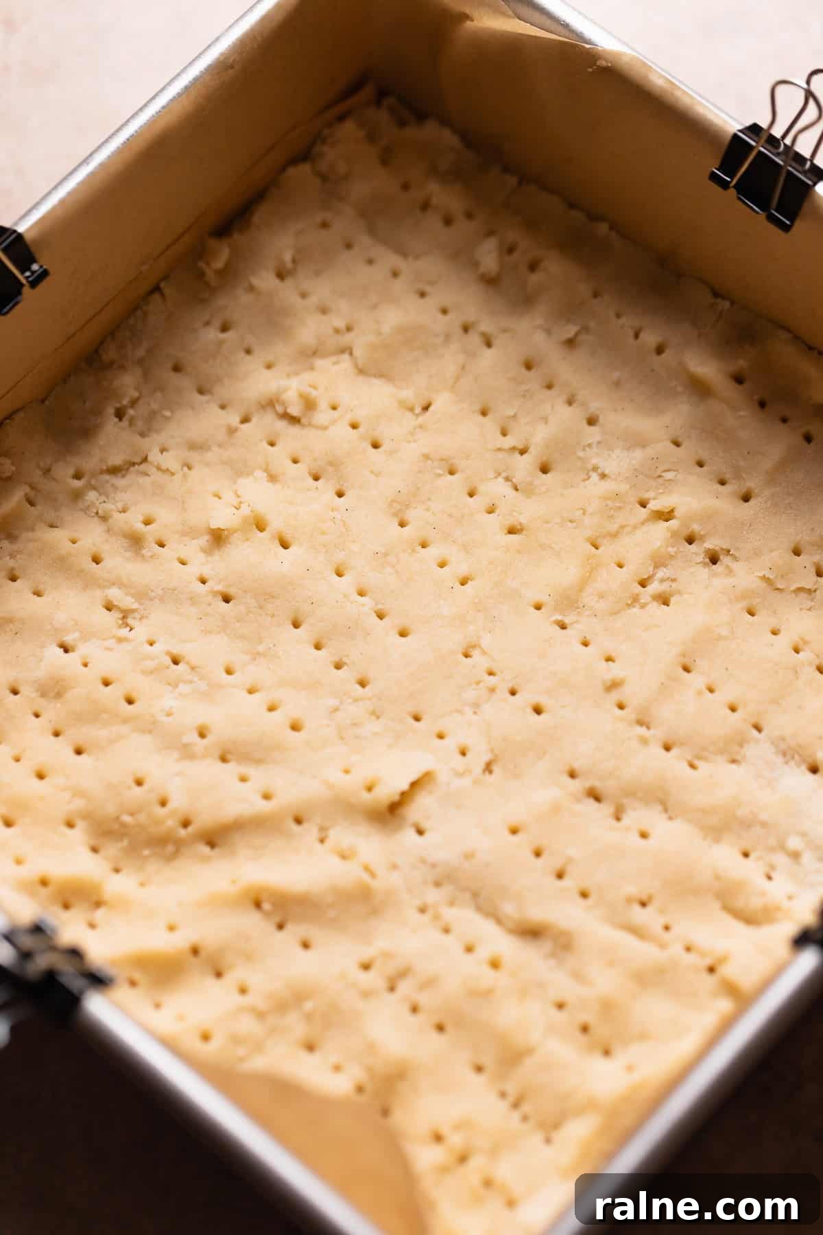 Classic Lemon Bars with Buttery Shortbread Crust 4 Shortbread dough pressed into a square pan pricked with a fork before baking.
