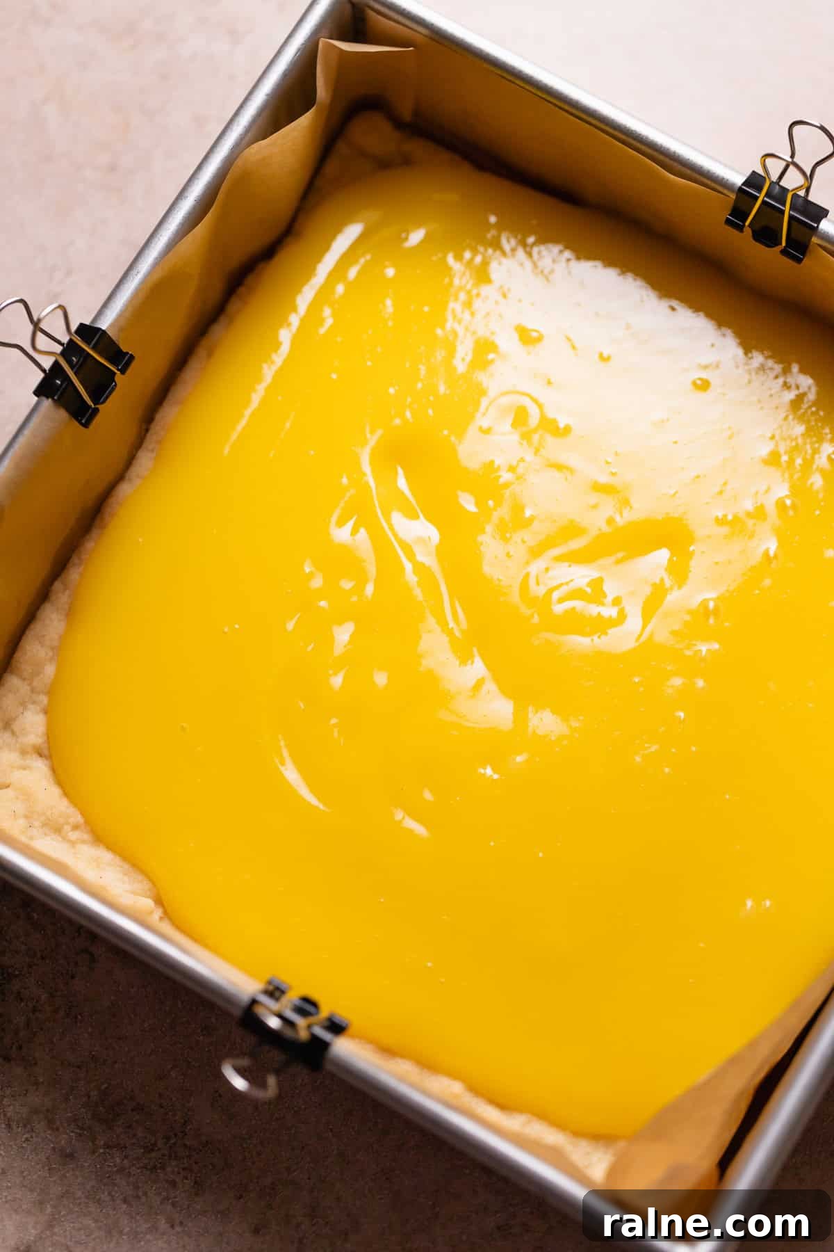 Classic Lemon Bars with Buttery Shortbread Crust 7 Lemon curd being spread over the top of the baked shortbread crust.