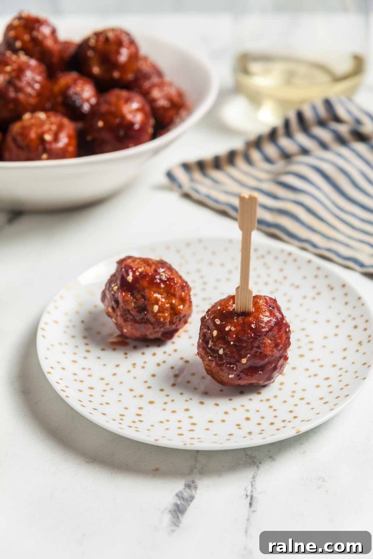 Spicy 4-Ingredient Cranberry Meatballs (Slow Cooker) 9 Two cranberry chili meatballs on an appetizer plate.