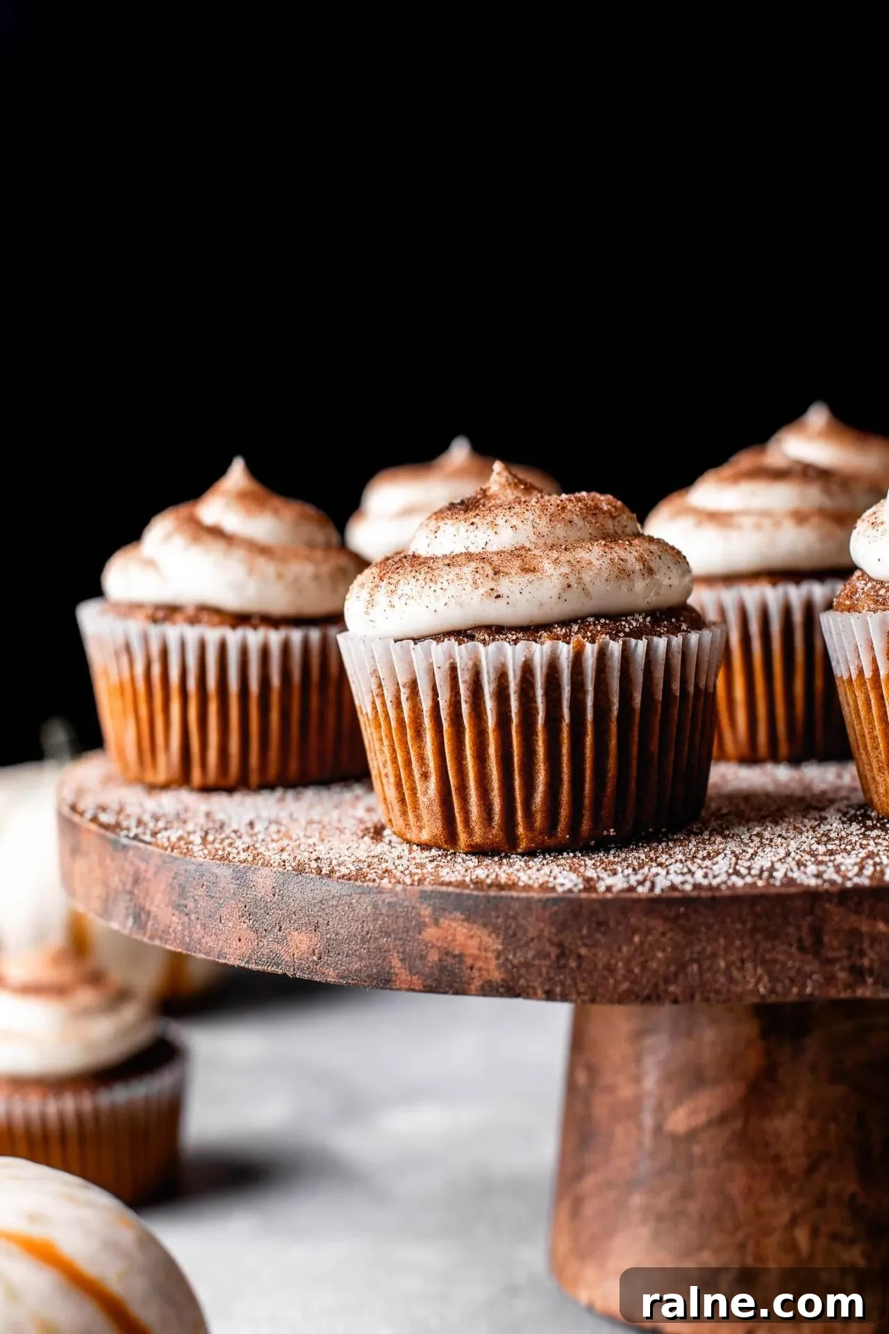 Pumpkin Spice Latte Cupcakes: Moist Espresso-Infused Fall Treats 2 frosted pumpkin spice latte cupcakes on wooden cake stand with pumpkin spice sugar sprinkled on top (7)