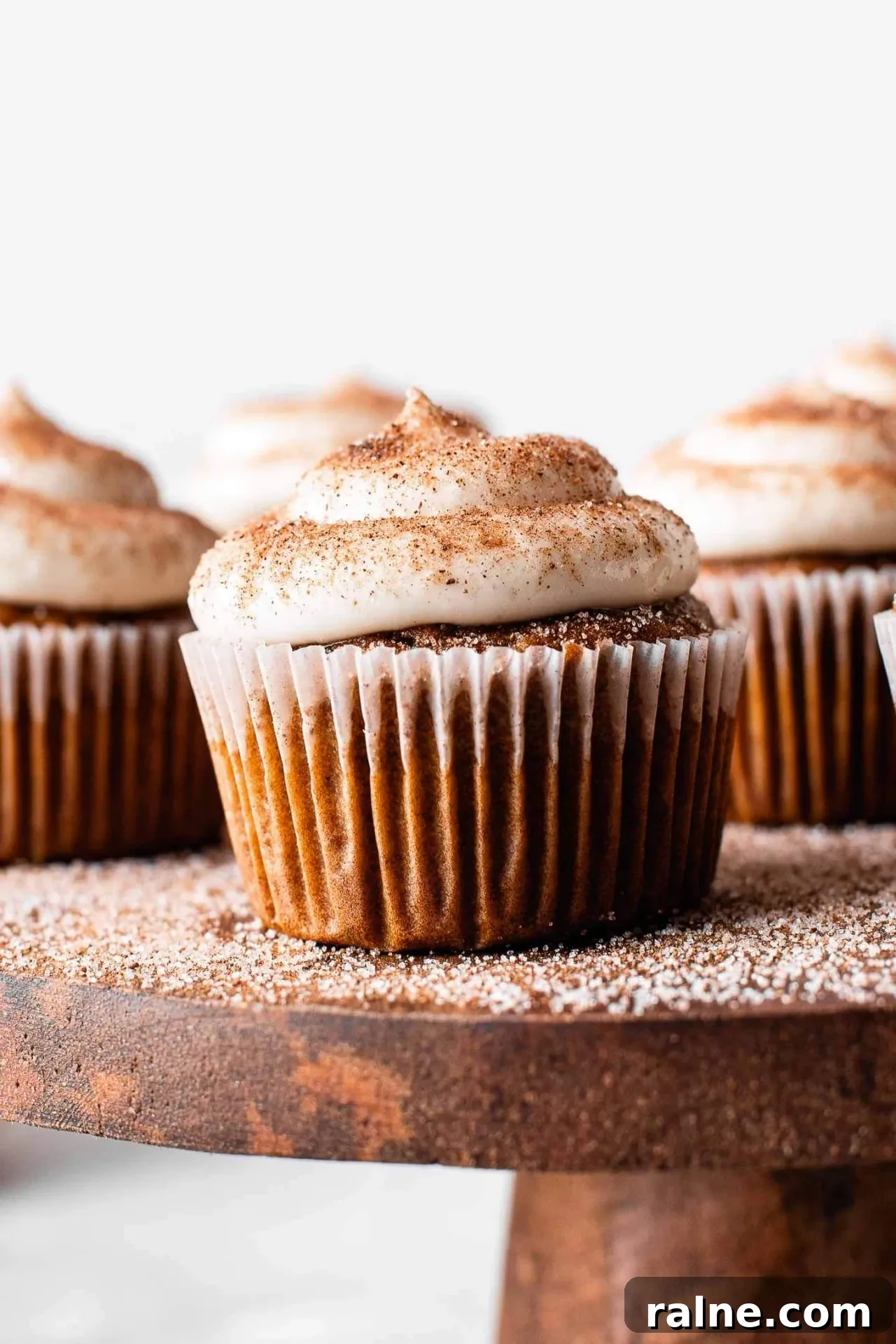 Pumpkin Spice Latte Cupcakes: Moist Espresso-Infused Fall Treats 12 frosted pumpkin spice latte cupcakes on wooden cake stand with pumpkin spice sugar sprinkled on top (5)