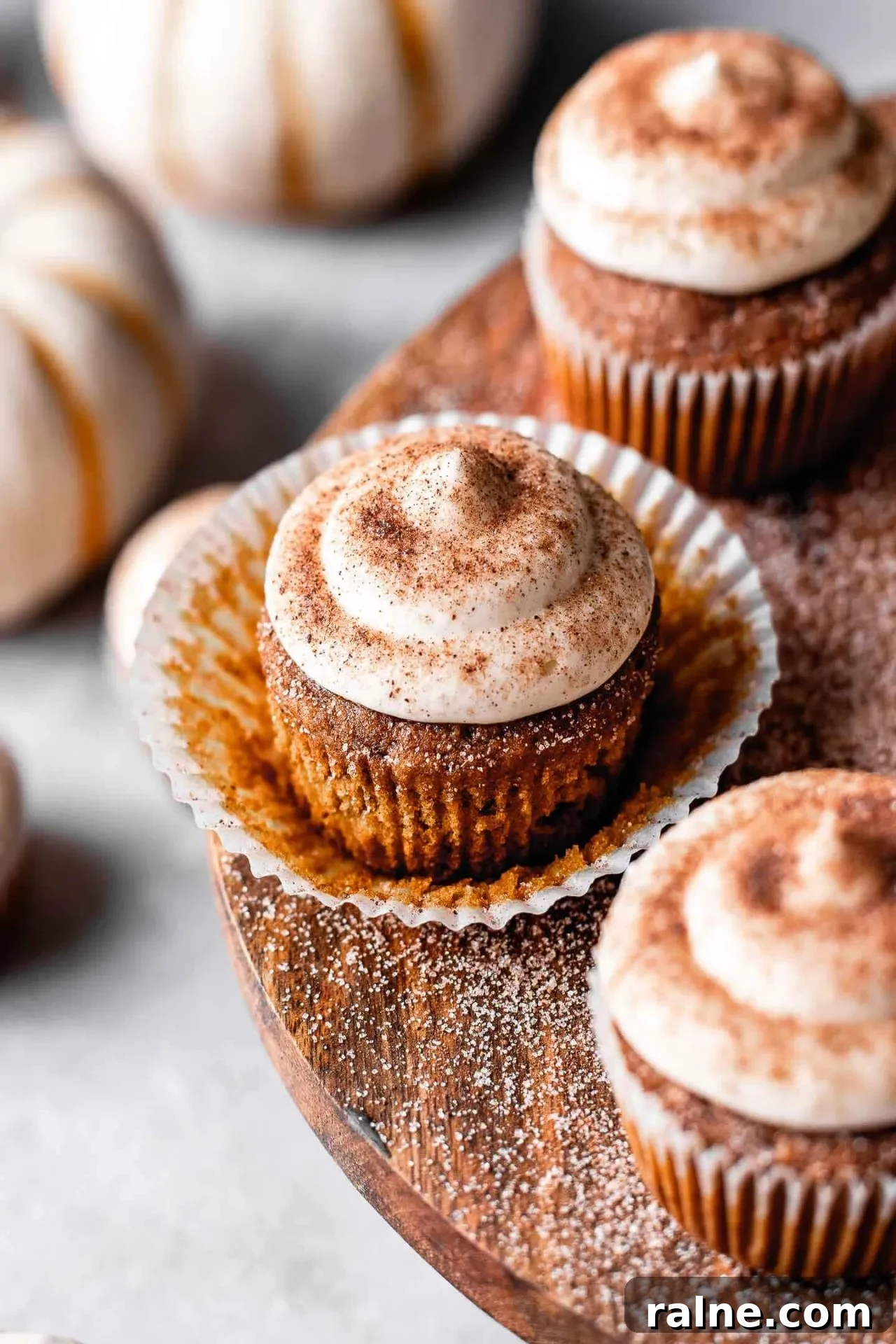 Pumpkin Spice Latte Cupcakes: Moist Espresso-Infused Fall Treats 3 frosted pumpkin spice latte cupcakes on wooden cake stand with pumpkin spice sugar sprinkled on top (9)
