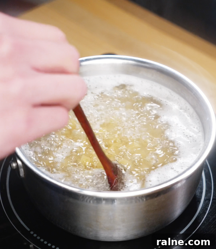 Pasta cooking in a bubbling pot of salted water, stirred with a wooden chopstick just before draining.