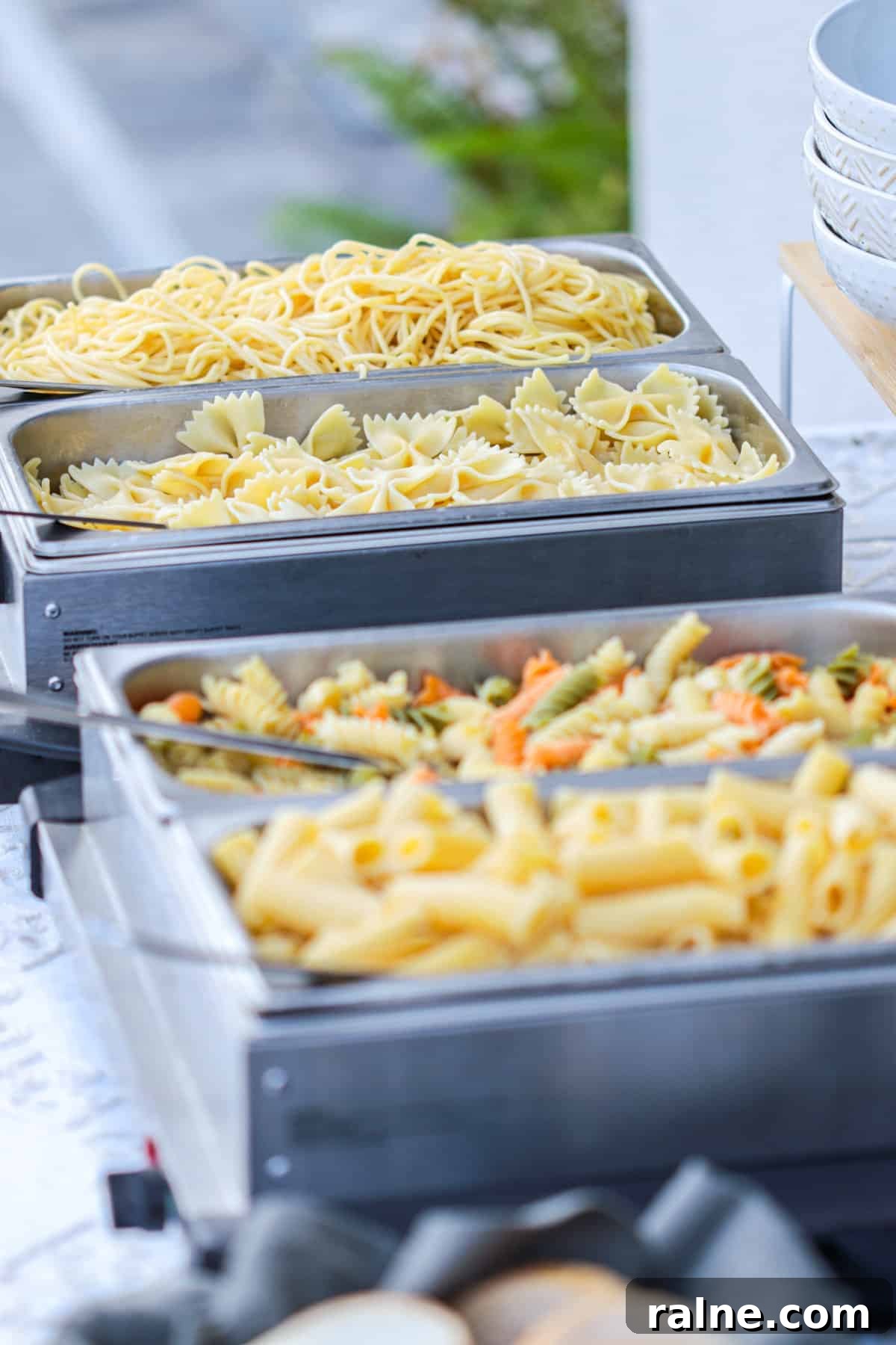 Party Pasta Bar Ideas: How to Set Up a Crowd-Pleasing Pasta Station 9 Pasta in chafing dishes on a buffet table.