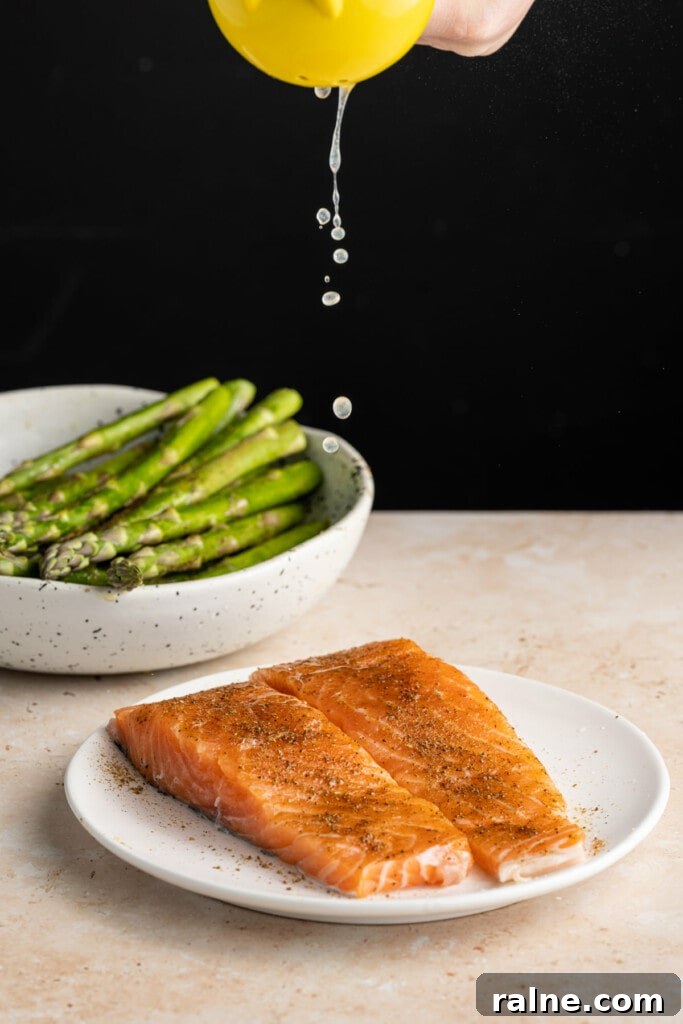 Squeezing lemon juice onto raw salmon before roasting.